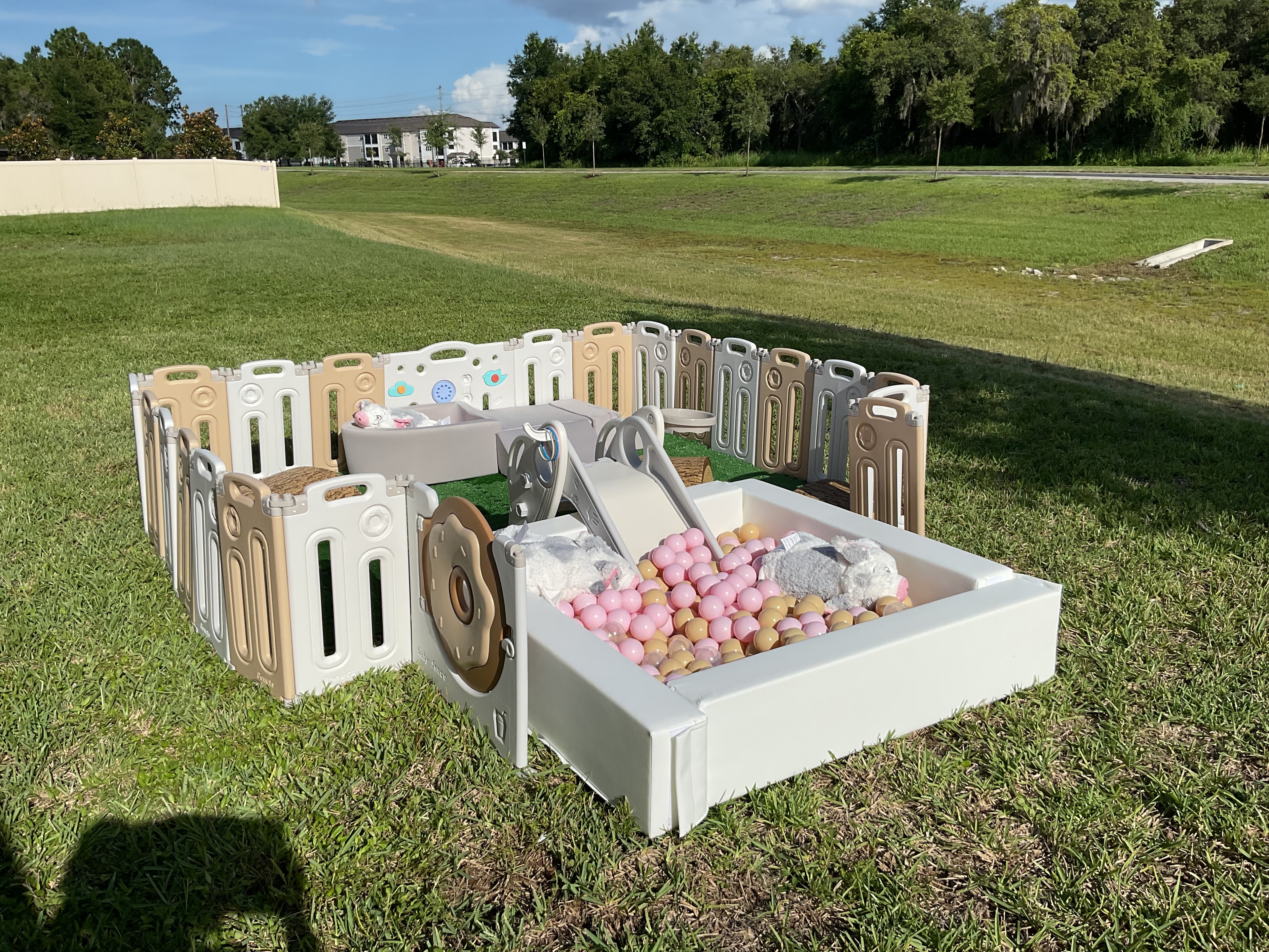 Pink soft play ball pit with fencing and slide in a backyard